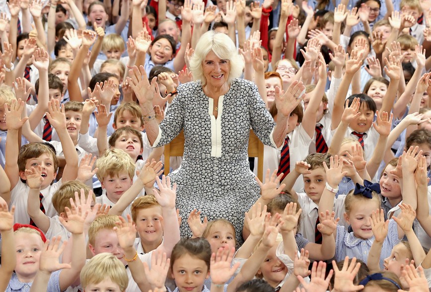 IN GOOD HANDS: Queen Camilla and schoolchildren raise their hands in celebration at a literary festival in London.