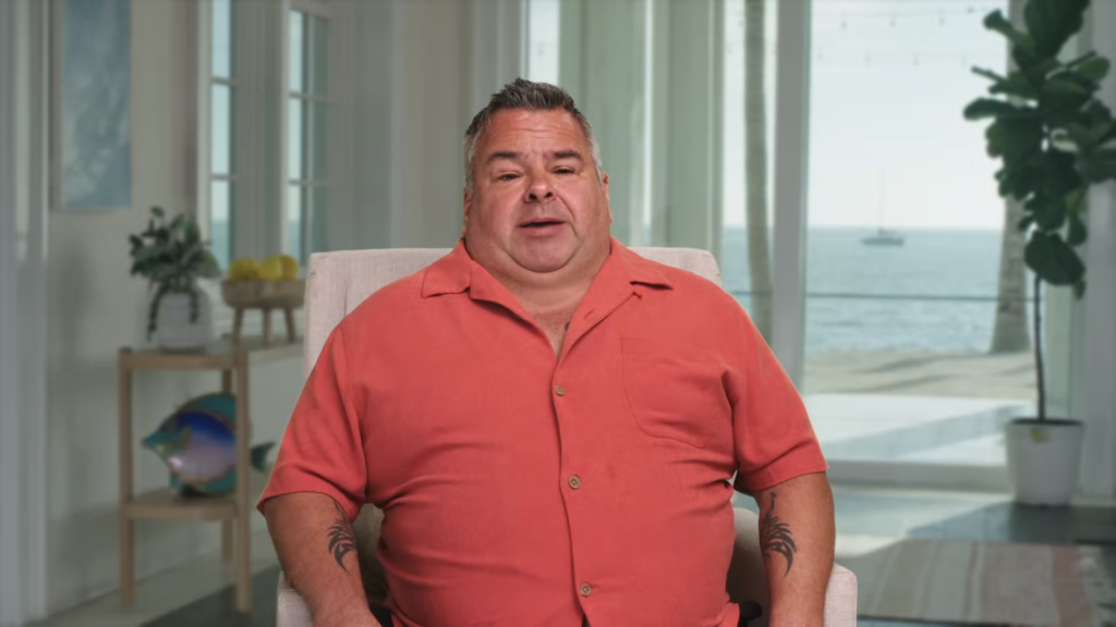 Ed Brown wears a salmon-colored collared shirt as he speaks to the camera while seated.