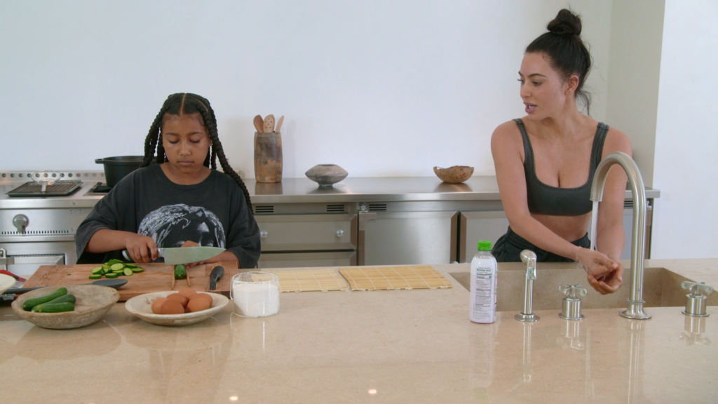 North West and Kim Kardashian work at the kitchen counter.