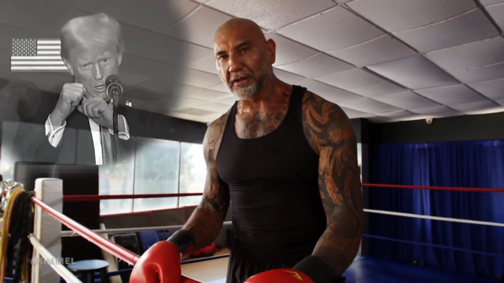 A photo of Dave Bautista wearing boxing gloves in a gym, while a sinister and frankly sad image of disgraced former President Donald Trump appears superimposed in the corner of the screen.