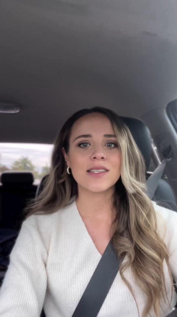 Jinger Duggar faces phone camera while driving.