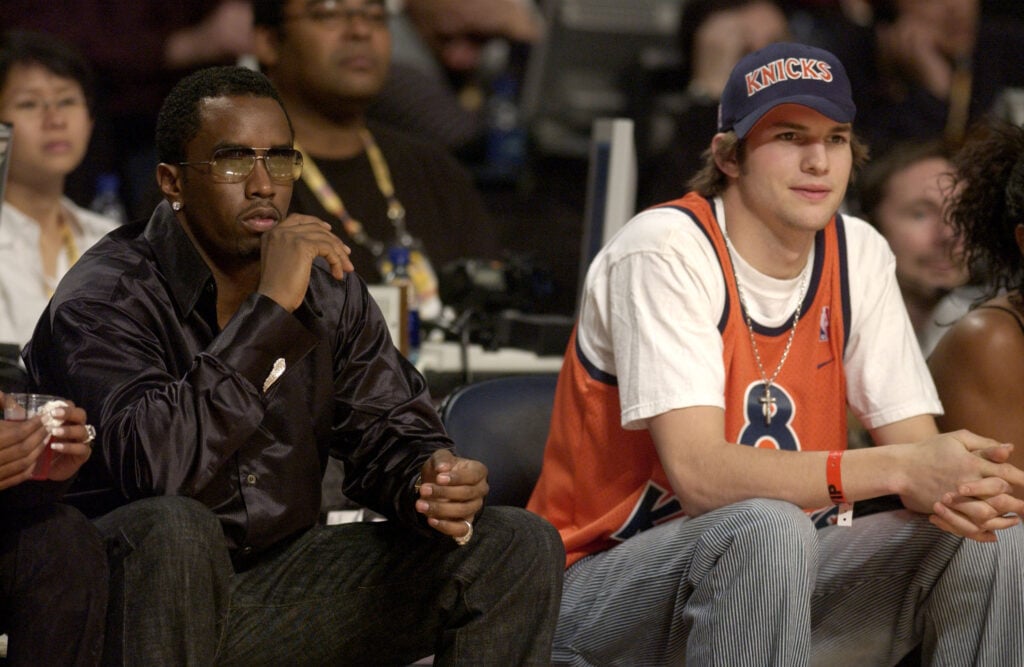 Rapper Sean P. Diddy Combs and actor Ashton Kutcher watch the action during the 2003 NBA All-Star Game at Phillips Arena on February 9, 2003 in Atlanta, Georgia.  